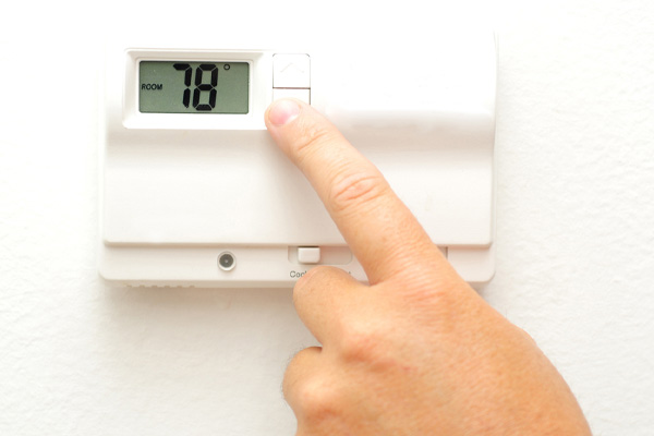 image of homeowner adjusting thermostat that controls hvac system