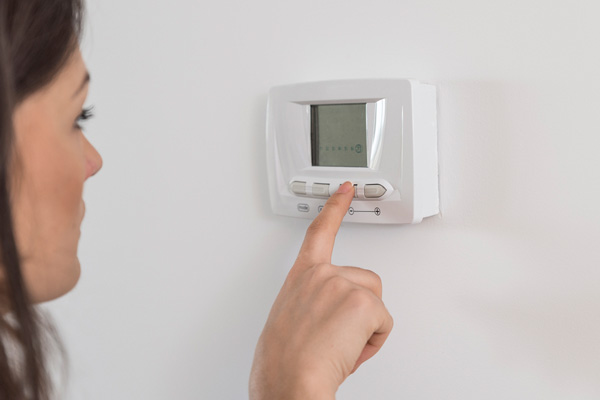 image of homeowner adjusting air conditioner thermostat 