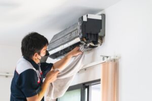 Professional technician cleaning ductless AC indoor unit