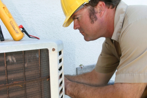 HVAC technician examining screeching air conditioner