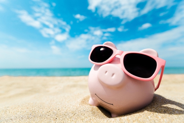 image of piggy bank in sunglasses by the beach depicting summer savings