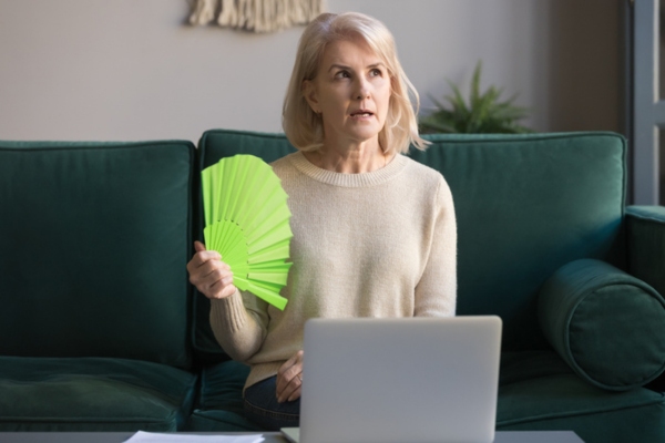 woman feeling warm and using hand fan due to old poor air flow of old AC