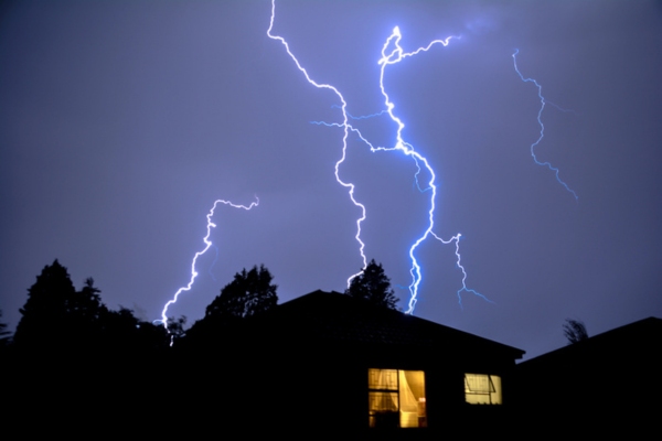 house with light at night during a lightning storm depicting power supply without interruption