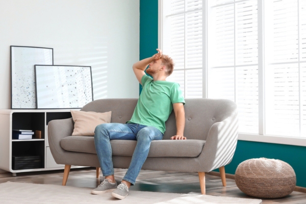 man feeling warm looking at home air conditioner depicting overcharged AC symptoms