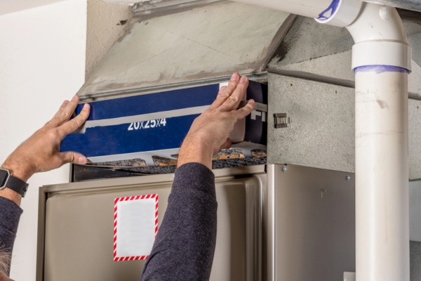 cropped view of a man's hands replacing furnace filter