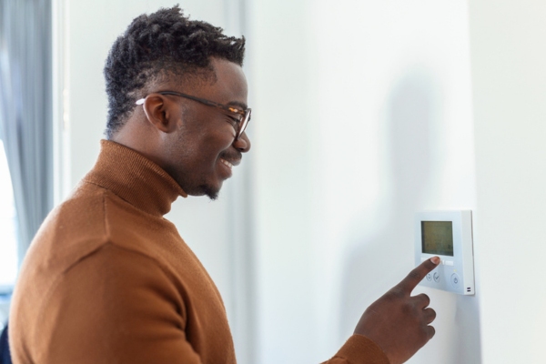 man adjusting central heating thermostat