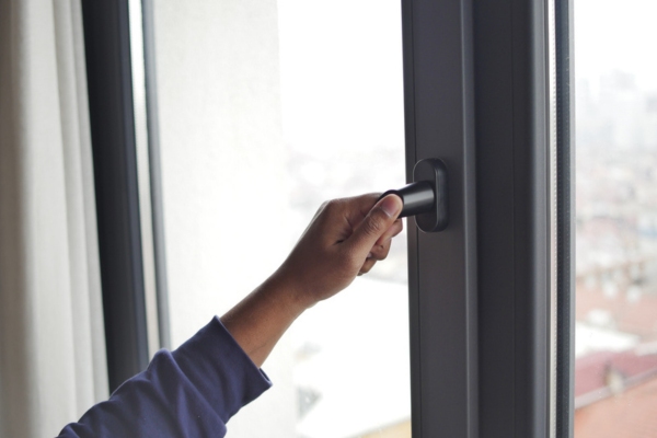 cropped view of a man's hand inspecting window for air leaks using his hand