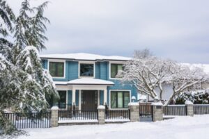 house during winter with snow on roof and trees