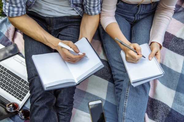 cropped view of a couple writing notes depicting comparing will call vs automatic oil delivery