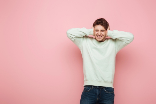 man covering ears due to banging furnace noises