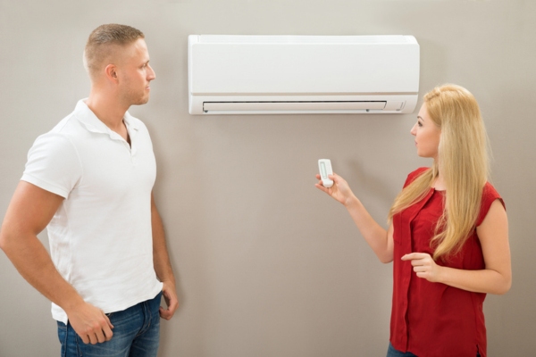 couple turning on ductless air conditioner at home