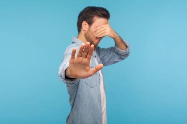 man covering eyes while doing a stop sign depicting ignoring warning signs of AC trouble