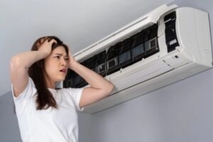 woman feeling stressed while looking at indoor ductless AC unit