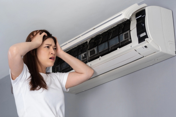 woman feeling stressed while looking at indoor ductless AC unit woman feeling stressed while looking at indoor ductless AC unit
