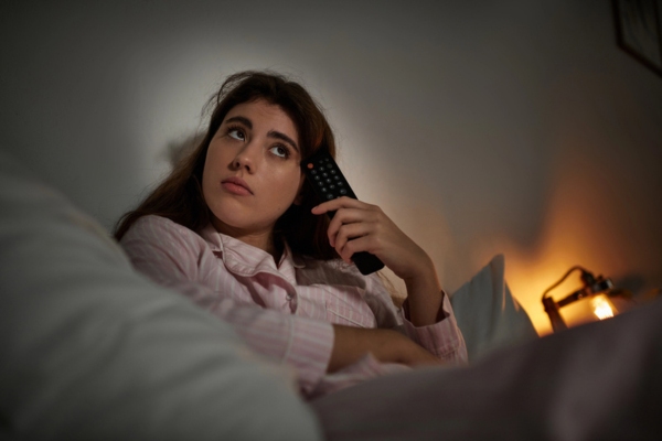 woman looking up while holding a remote getting ready to sleep depicting unstable power supply from a generator