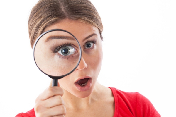woman looking through a magnifying glass depicting Inspect and Monitor oil tanks