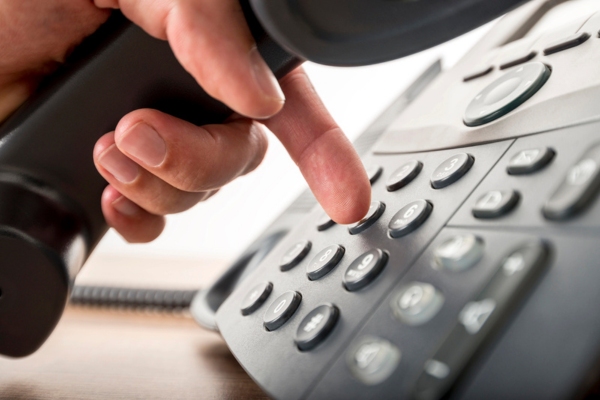closeup of homeowner dialing from a home phone calling a Professional HVAC Technician