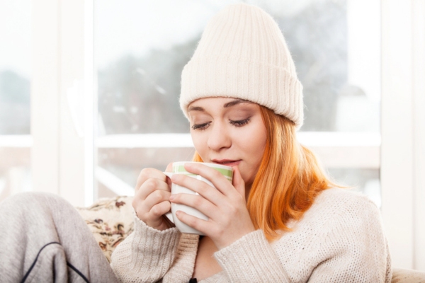 woman keeping warm while drinking coffee during winter