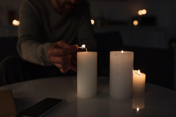 Cropped view of man in darkness lighting candles due to power outage