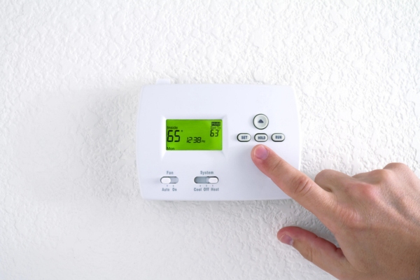 man adjusting digital thermostat