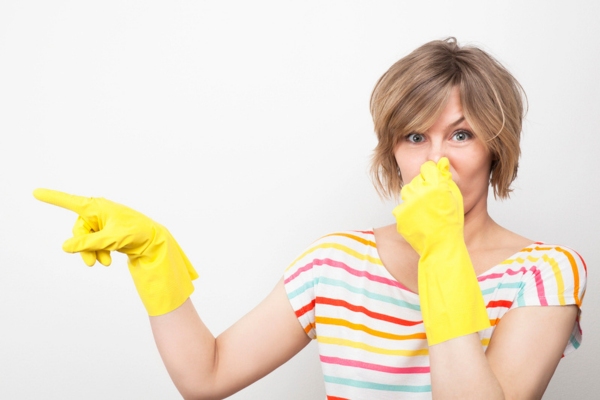 woman wearing yellow rubber gloves covering her nose due to dead animal in air duct