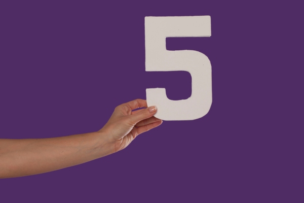 Female hand holding up the number 5