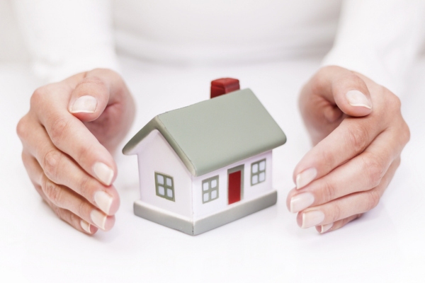 hand protecting miniature house depicting Protect Your Home From Common Air Conditioning Scams