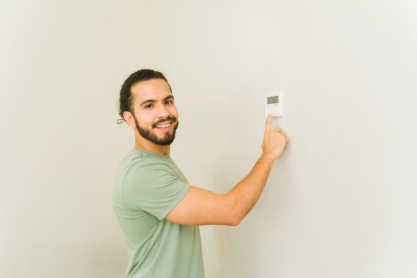 man controlling indoor temperature using programmable thermostat
