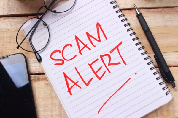 scam alert written on a notebook using red ink