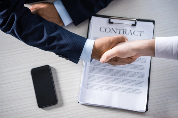 two men's hands shaking with contract on the table