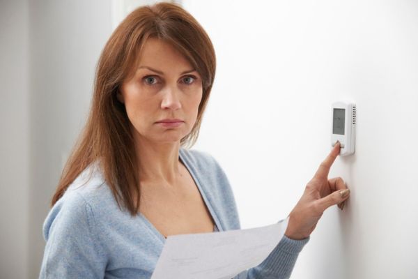 worried woman controlling home thermostat